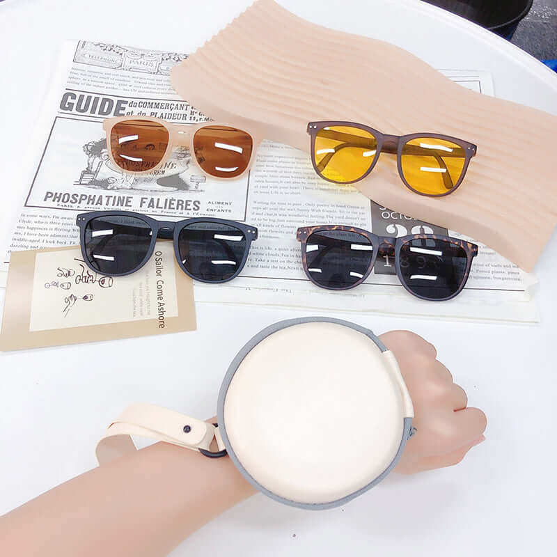 Trendy Foldable Sunglasses For Women TR Polarized Folding Sun Glasses displayed on a table with a hand and a holder.