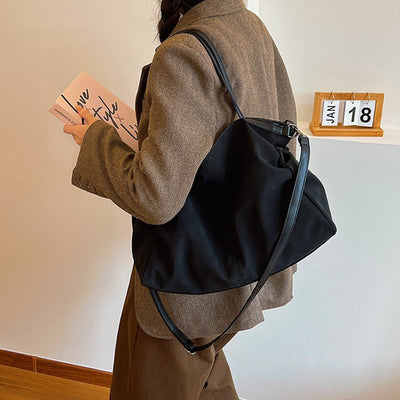Woman holding a book while wearing a Versatile Large-Capacity Women's Bag in black.