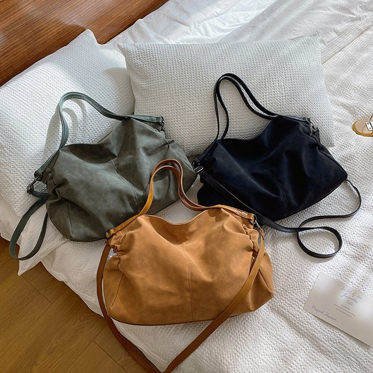 Versatile Large-Capacity Women's Bag in green, black, and brown on a bed, perfect for travel and everyday use.
