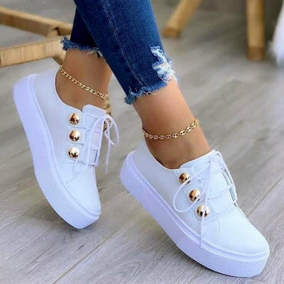 Light Breathable Female Running Shoes Casual Women Sneakers in white with gold accents, paired with ripped jeans.