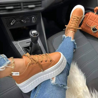 Casual platform women's sneakers in brown worn with ripped jeans inside a car.