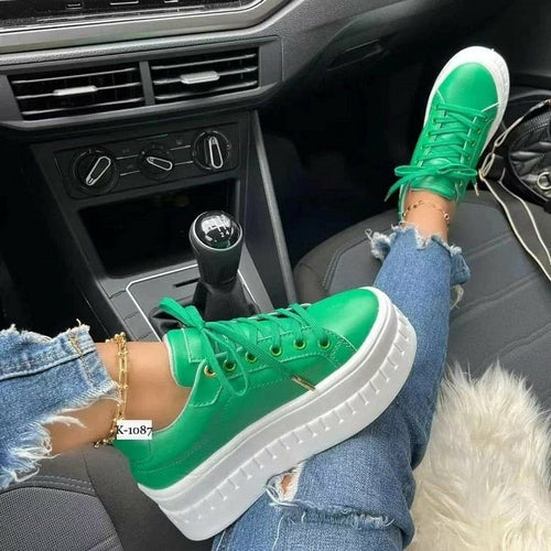 Casual platform women's sneakers with green color design on a foot in a car interior.