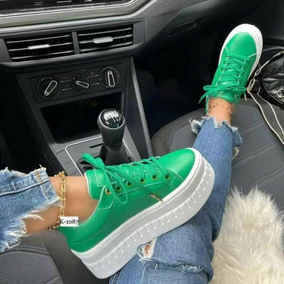 Casual platform women's sneakers with green color design on a foot in a car interior.