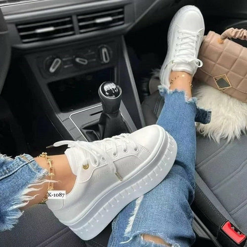 Casual platform women's sneakers worn with distressed jeans in a car interior.